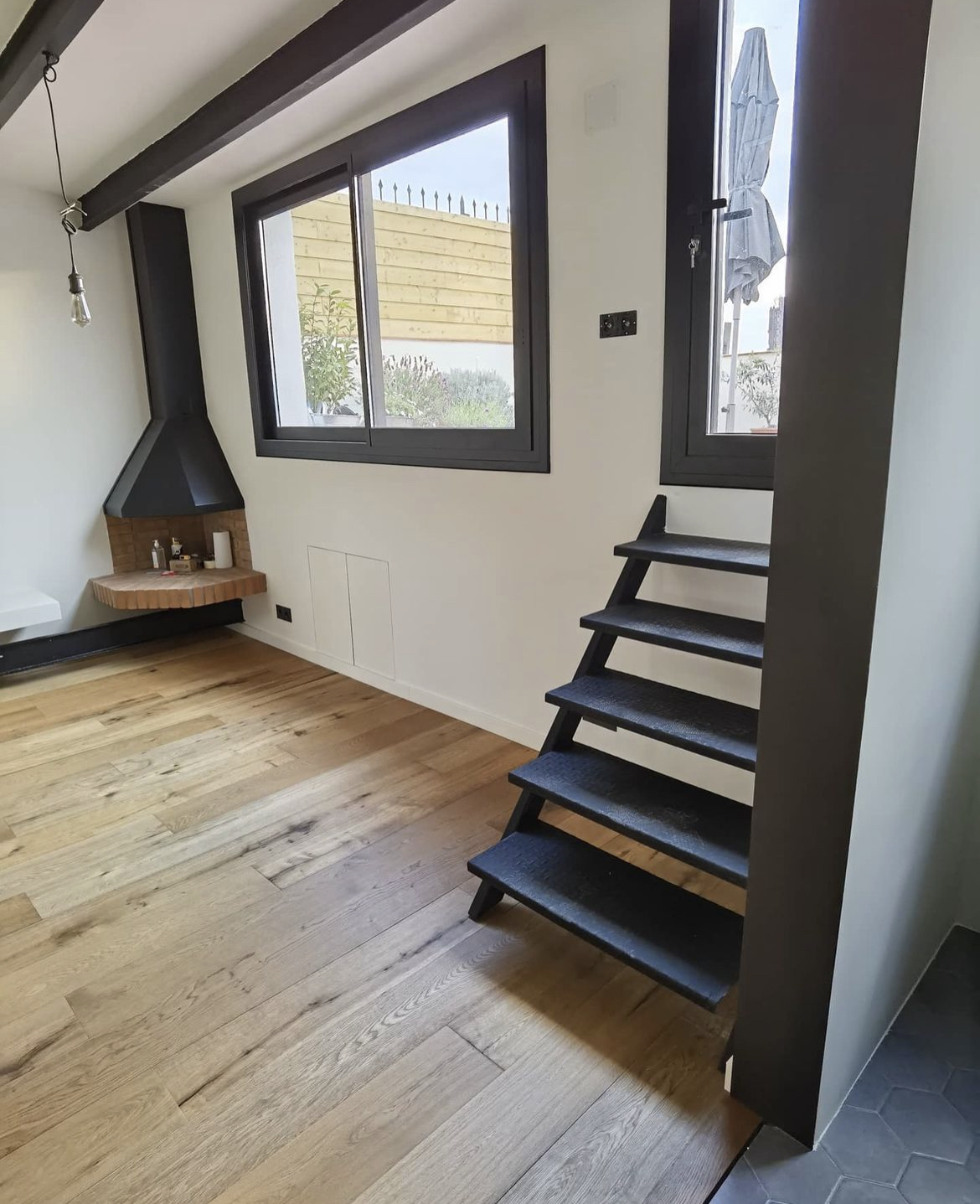 Reforma de dúplex o altillo con escalera metálica negra y chimenea en Eixample Barcelona