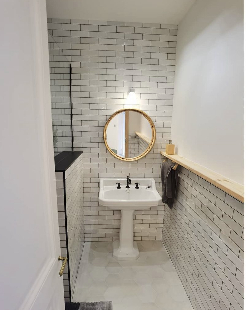 Aseo de cortesía estilo clásico con lavabo con pedestal y espejo redondo en Eixample Barcelona