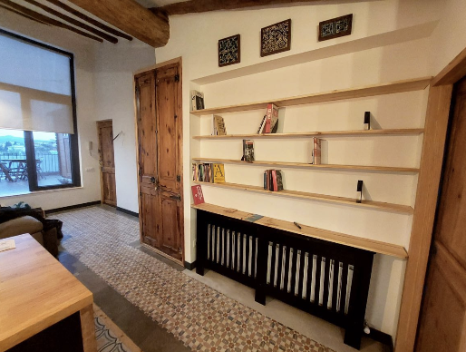 Restauración integral de pasillo con puerta de madera antigua y estantería a medida en Manresa