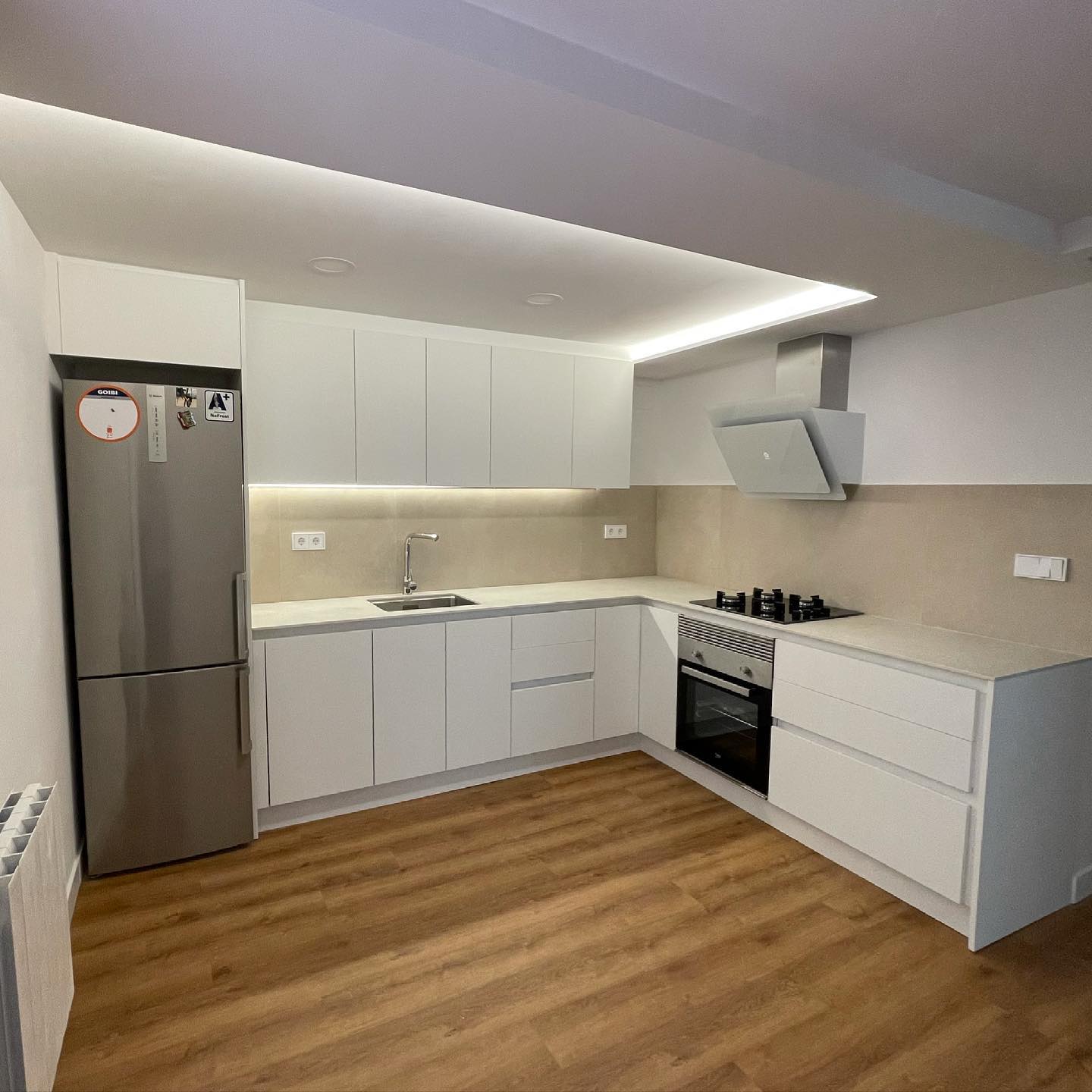 Reforma de cocina blanca de diseño en L con suelo de parquet en Gràcia Barcelona
