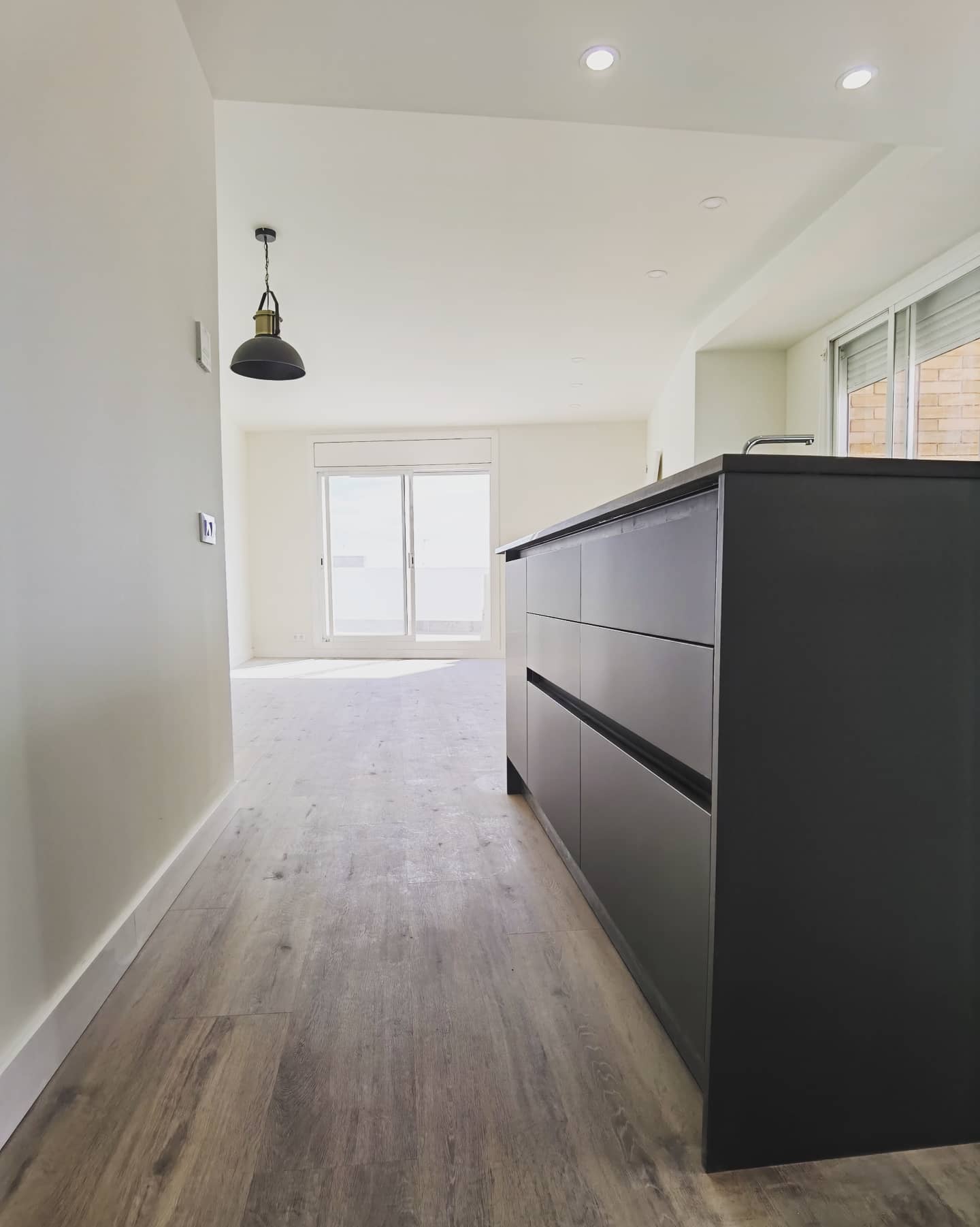 Reforma integral con cocina abierta e isla central en negro mate en Sant Andreu Barcelona