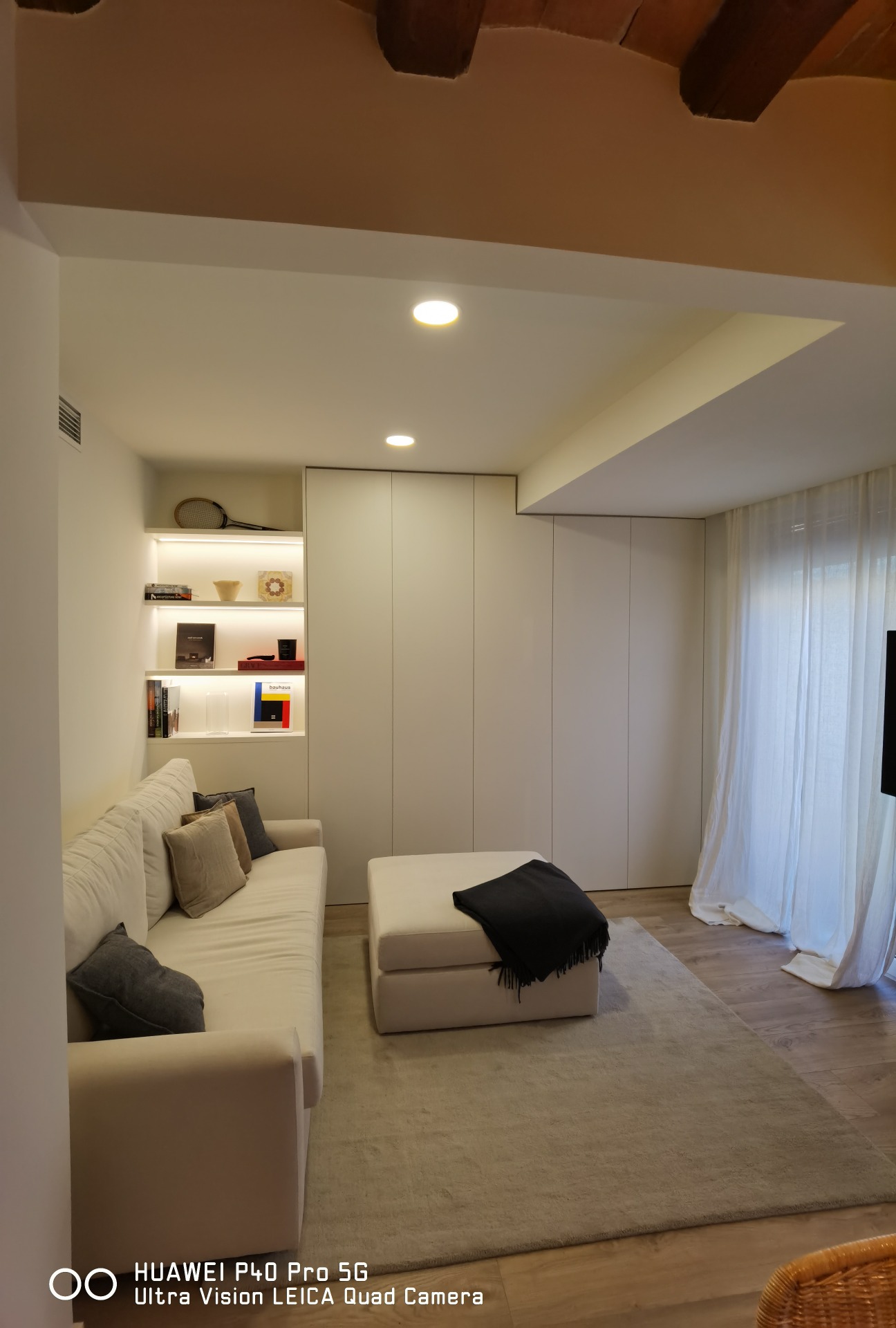 Diseño de salón minimalista con iluminación indirecta en estanterías y tonos neutros en Sarrià Barcelona