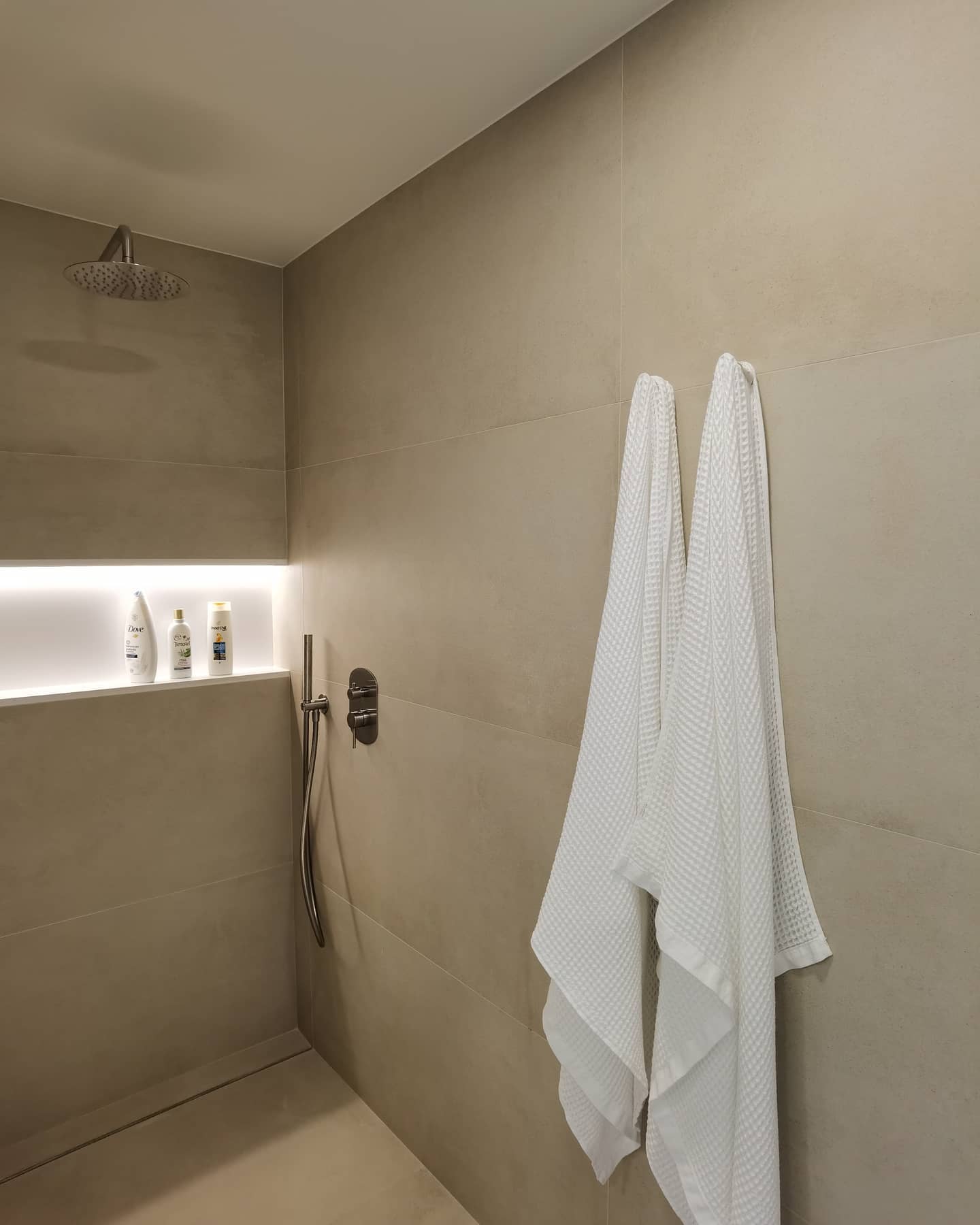 Ducha de diseño en tonos neutros con hornacina iluminada y rociador de techo en Sarrià Barcelona