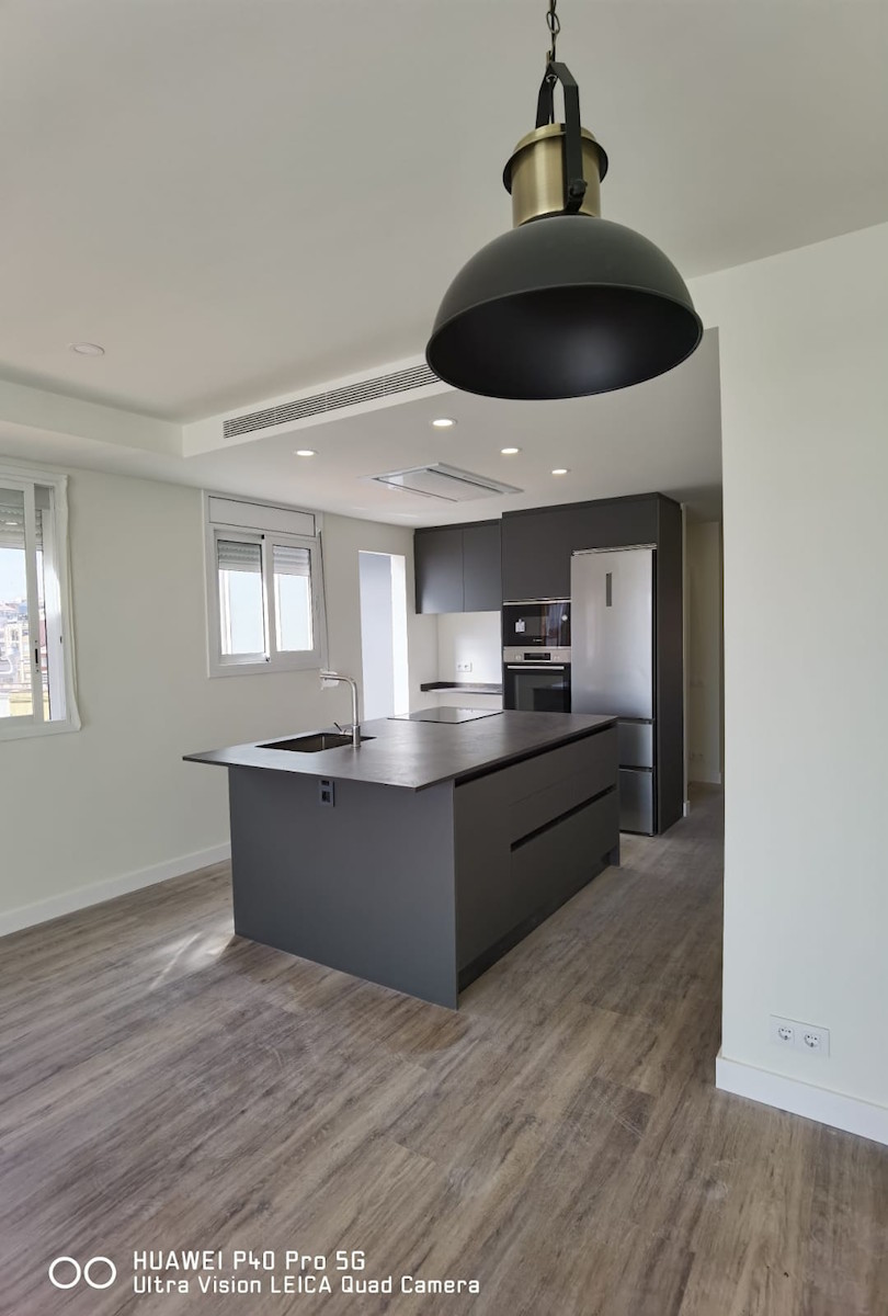 Reforma integral con cocina abierta e isla central en negro mate en Sant Andreu Barcelona