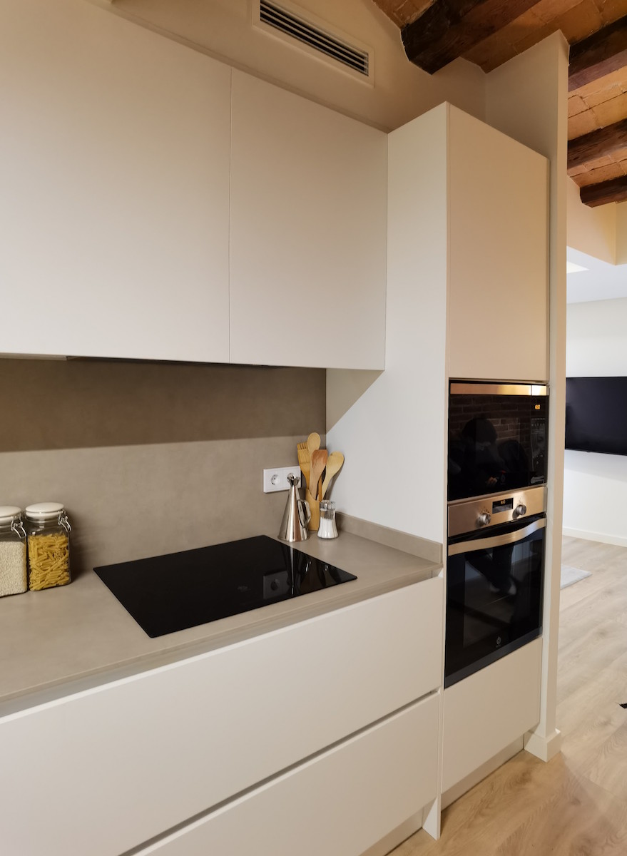 detalle de cocina abierta a comedor, linea protagonista de mobiliario, cocina en blanco mate, luz indirecta, ladrillo restaurado en SARRIA Barcelona