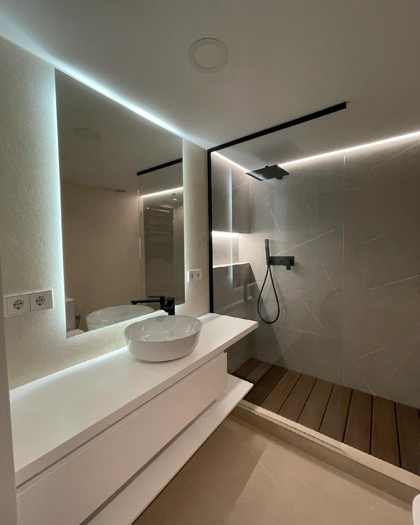 Reforma de baño completo de diseño con espejo retroiluminado y grifería negra en Gràcia Barcelona