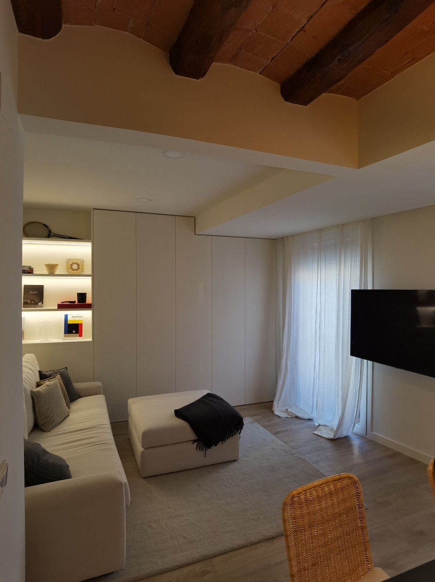 Reforma de salón principal en tonos neutros con iluminación indirecta y almacenaje a medida en Sarrià Barcelona