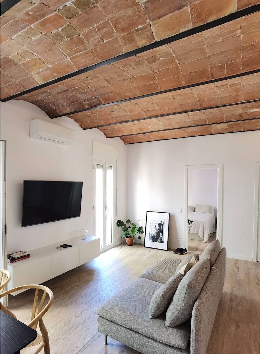 salón comedor con teche volta catalana restaurada, mobiliario nordico, suelo de roble, paredes blancas, luz indirecta